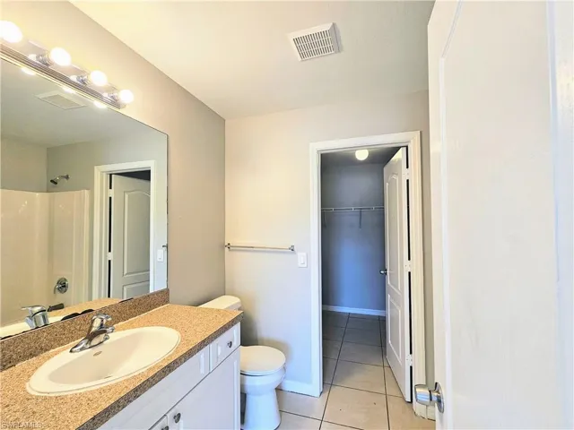 Full bath with light tile patterned floors, vanity, a shower, and a walk in closet