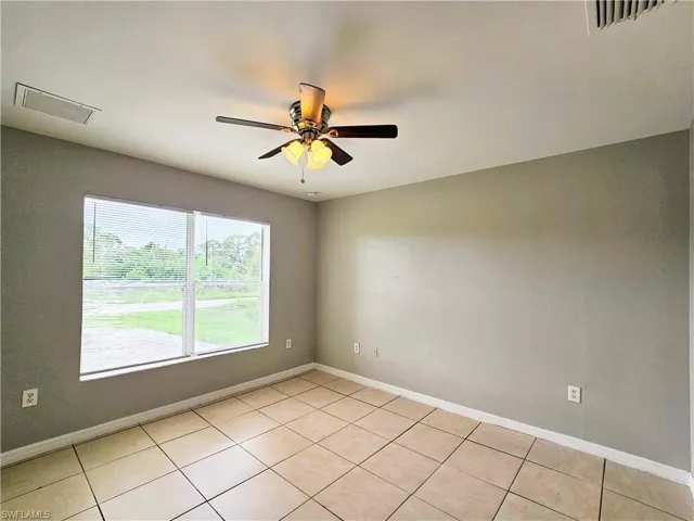 Empty room featuring light tile patterned flooring and ceiling fan