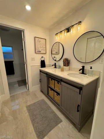 Bathroom featuring dual vanity, tile flooring, and a textured ceiling