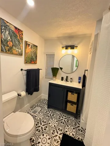 Bathroom featuring tile flooring, vanity, toilet, and a textured ceiling
