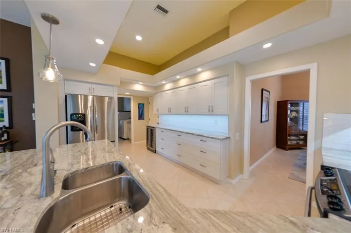 Kitchen with white cabinetry, stainless steel fridge with ice dispenser, and backsplash