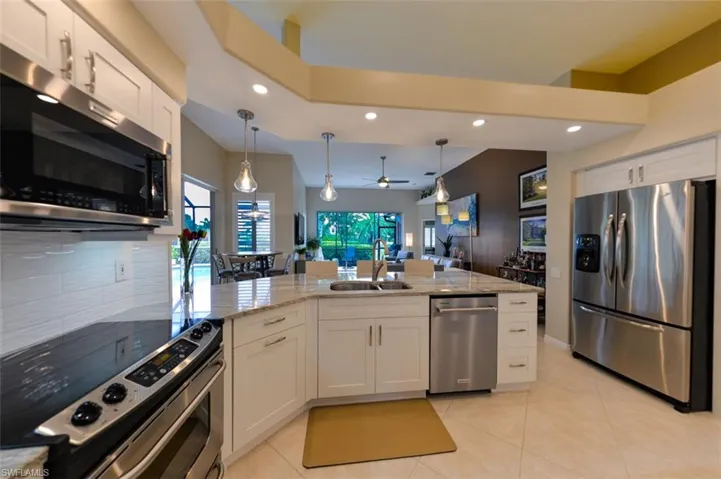Kitchen with ceiling fan, stainless steel appliances, backsplash, sink, and white cabinets