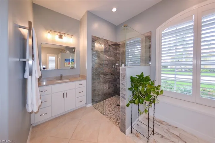 Bathroom with tile flooring, vanity with extensive cabinet space, and a shower with door