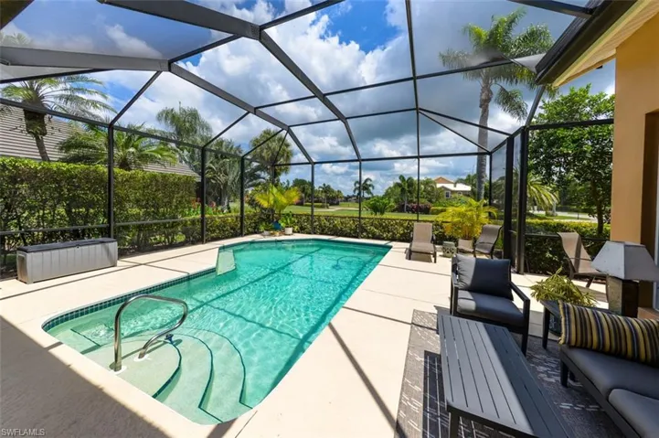 View of swimming pool featuring glass enclosure and a patio