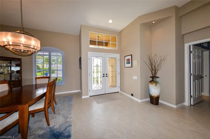 Tiled foyer entrance with a notable chandelier and french doors