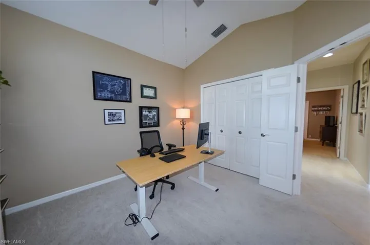 Office space featuring high vaulted ceiling and light colored carpet