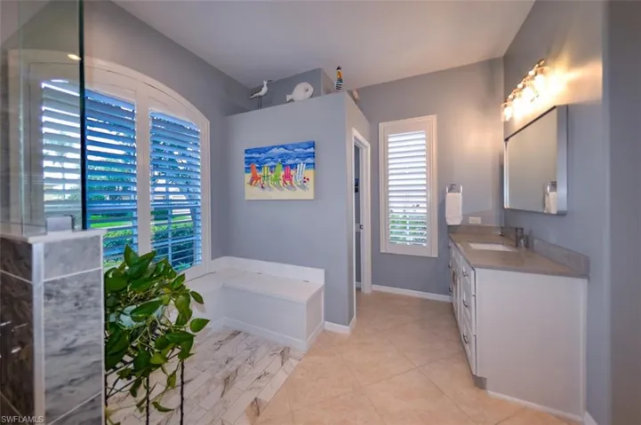 Bathroom featuring dual bowl vanity, tile flooring, and a bathing tub