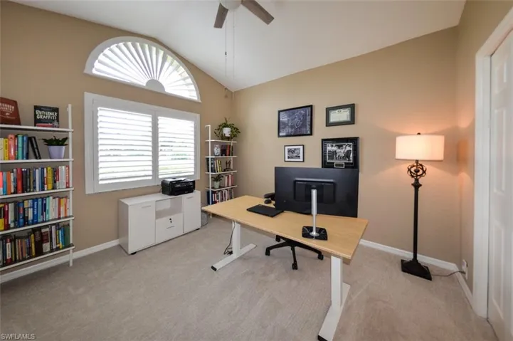 Home office with lofted ceiling, ceiling fan, and light colored carpet