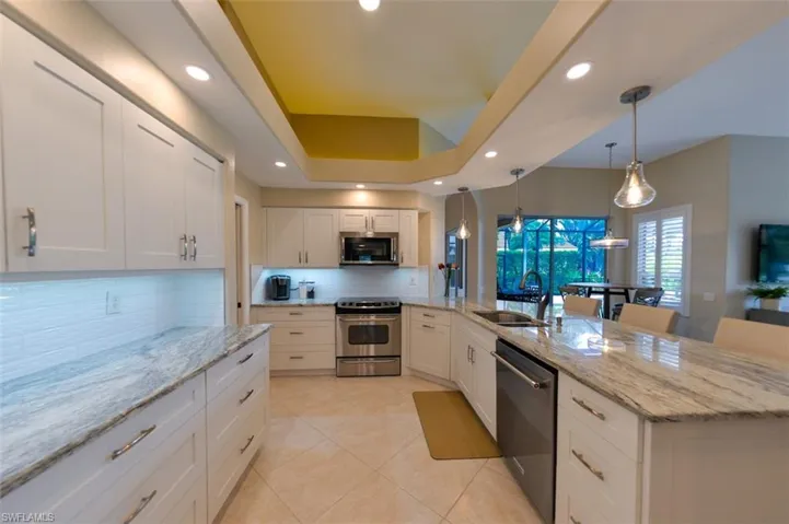 Kitchen with tasteful backsplash, pendant lighting, sink, white cabinets, and appliances with stainless steel finishes