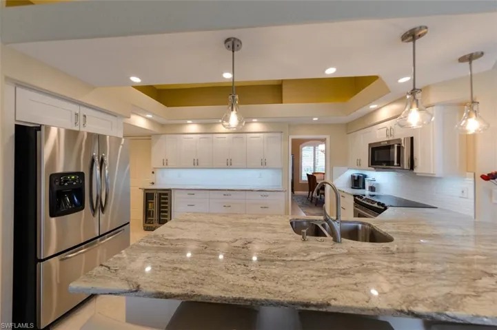 Kitchen featuring stainless steel appliances, white cabinets, and backsplash