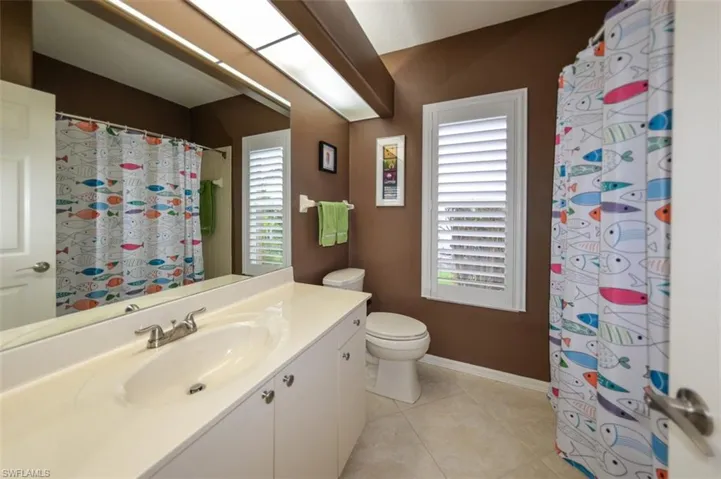 Bathroom with tile flooring, a healthy amount of sunlight, and vanity with extensive cabinet space