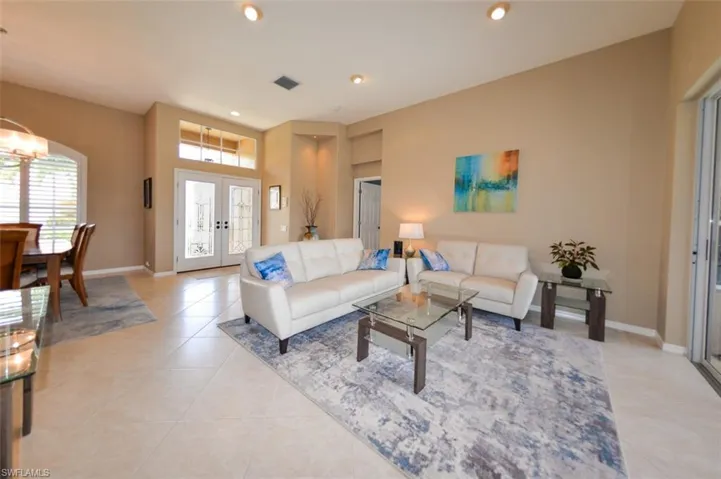 Living room featuring french doors, light tile floors, and an inviting chandelier