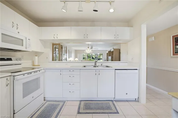 Kitchen with white appliances, white cabinetry, light countertops, and light tile patterned floors