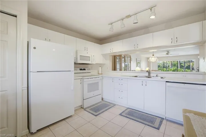 Kitchen featuring white appliances, light countertops, white cabinets, and ceiling fan