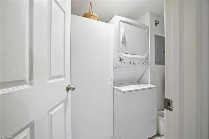 Laundry room with stacked washing machine and dryer and electric panel