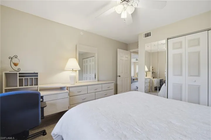 Bedroom featuring an office area, a closet, a ceiling fan, and dark colored carpet