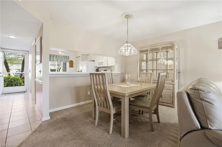 Dining space with light colored carpet and light tile patterned flooring