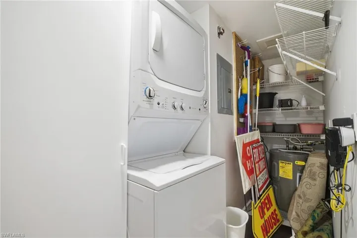 Laundry area featuring electric water heater, stacked washer / drying machine, and electric panel