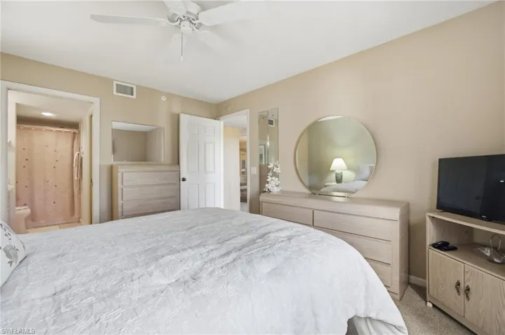 Carpeted bedroom featuring ceiling fan and ensuite bath