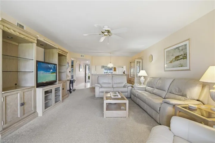 Carpeted living room featuring ceiling fan and a chandelier
