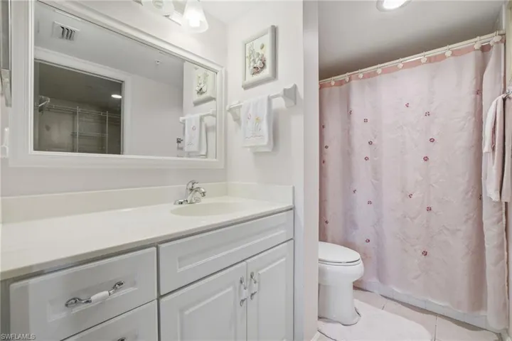 Bathroom featuring curtained shower, vanity, light tile patterned floors, and recessed lighting