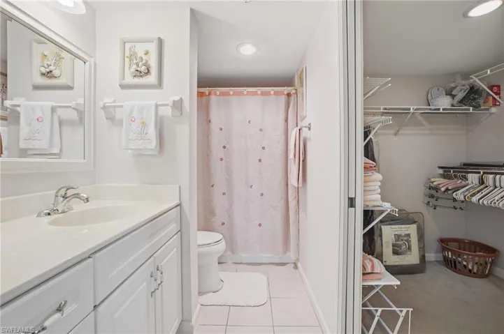 Full bathroom with a shower with shower curtain, vanity, a walk in closet, and light tile patterned floors