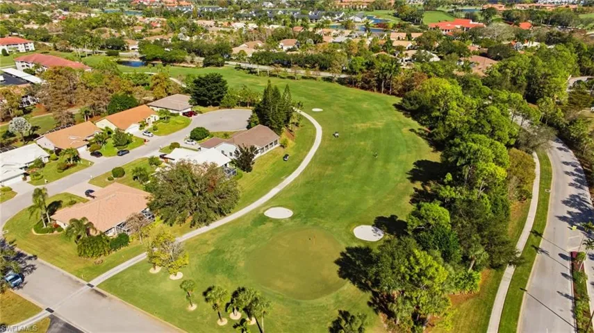 Aerial view of property and surrounding area featuring a local golf course and nearby suburban area