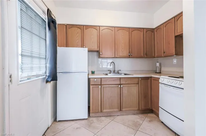 Kitchen with white appliances, tasteful backsplash, light countertops, and brown cabinets