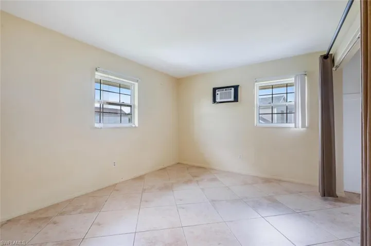 Unfurnished bedroom with a closet, light tile patterned floors, and a wall mounted AC
