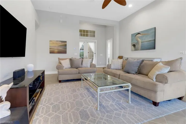Tiled living room with a high ceiling, french doors, and ceiling fan