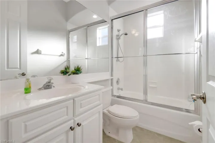 Full bathroom with vanity, toilet, shower / bath combination with glass door, and tile patterned flooring