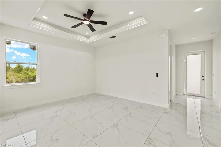 Unfurnished room with baseboards, recessed lighting, a ceiling fan, a raised ceiling, and light marble finish floors