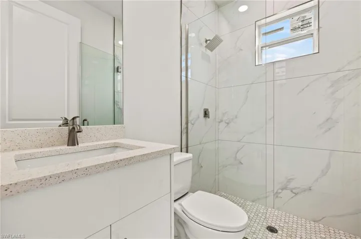 Full bathroom featuring toilet, vanity, and a marble finish shower