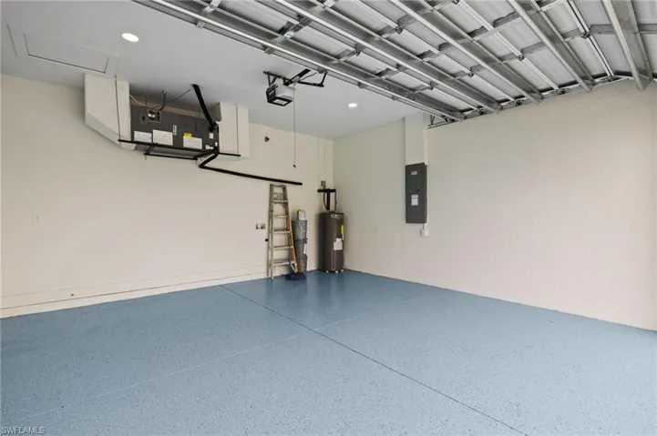 Garage featuring electric water heater, a garage door opener, and electric panel
