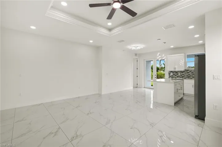Unfurnished room featuring a ceiling fan, recessed lighting, baseboards, a raised ceiling, and ornamental molding