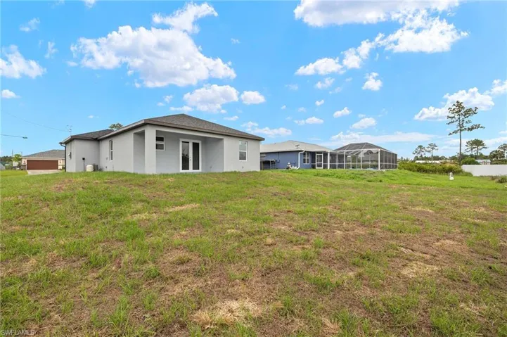 Rear view of property featuring a lawn and stucco siding