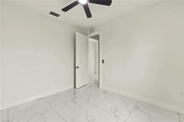 Empty room with light marble finish floors, baseboards, and a ceiling fan