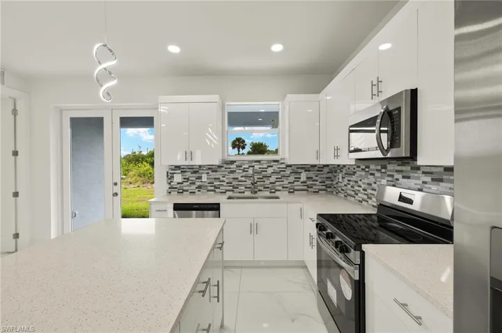 Kitchen with appliances with stainless steel finishes, a sink, plenty of natural light, white cabinetry, and recessed lighting