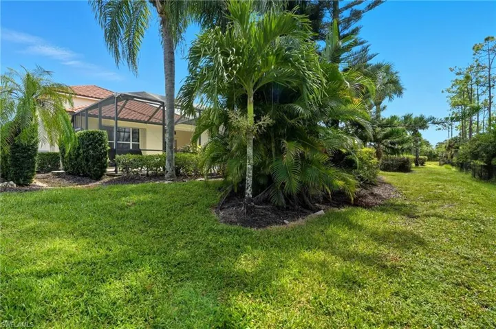View of green lawn with a lanai and a sunroom