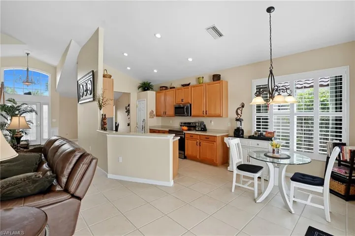 Kitchen featuring hanging light fixtures, a chandelier, appliances with stainless steel finishes, recessed lighting, and high vaulted ceiling