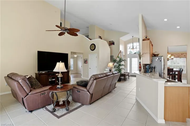 Living area featuring high vaulted ceiling, healthy amount of natural light, light tile patterned floors, ceiling fan