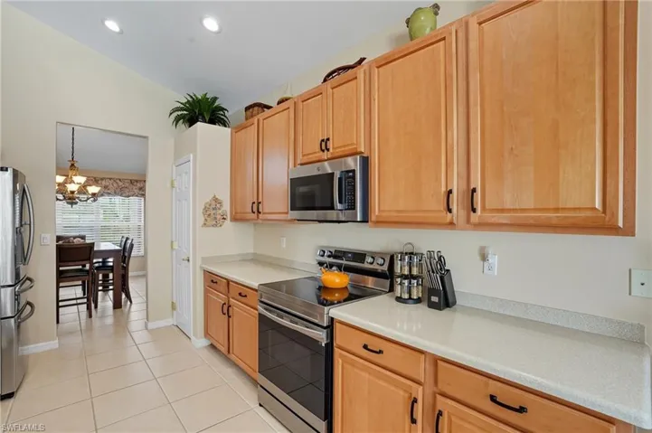 Kitchen with stainless steel appliances, light countertops, lofted ceiling, a chandelier, and hanging light fixtures