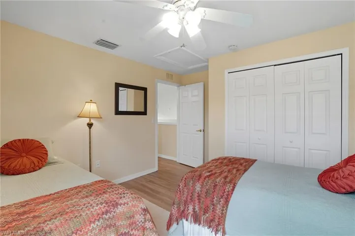 Bedroom featuring light wood-style flooring, attic access, ceiling fan, and a closet
