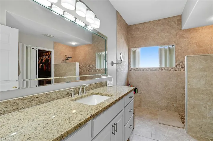 Full bathroom with a spacious closet, vanity, a walk in shower, light tile patterned floors, and tile walls