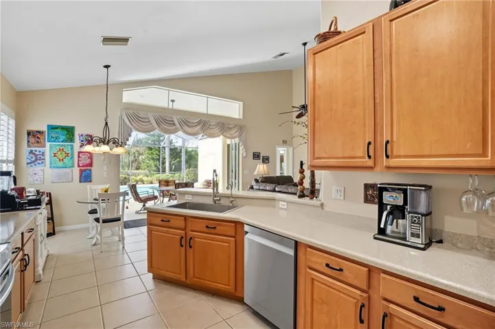 Kitchen featuring vaulted ceiling, stainless steel appliances, light tile patterned flooring, light countertops, and hanging light fixtures