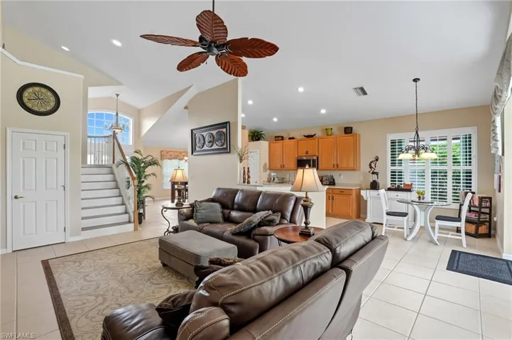 Living area with ceiling fan, light tile patterned flooring, recessed lighting, and stairway