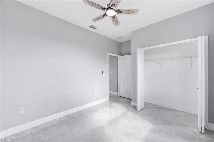 Unfurnished bedroom with ceiling fan and a closet