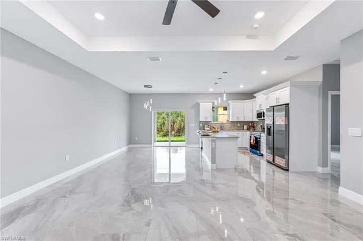 Kitchen with hanging light fixtures, ceiling fan, appliances with stainless steel finishes, a kitchen island, and white cabinetry