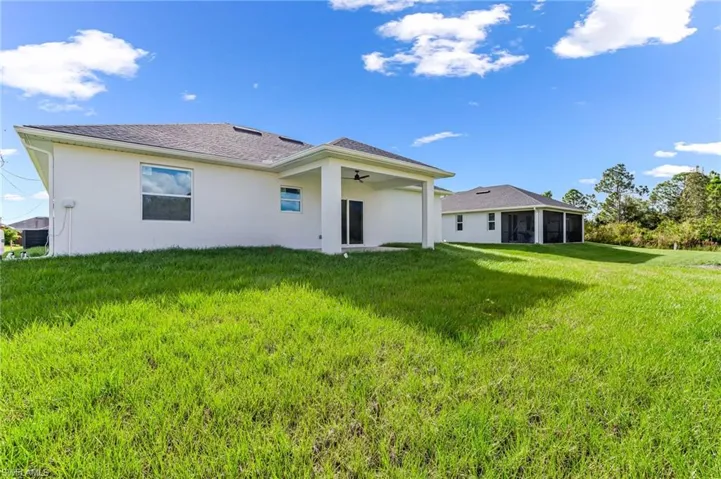 Rear view of property with a sunroom, central AC, ceiling fan, and a lawn