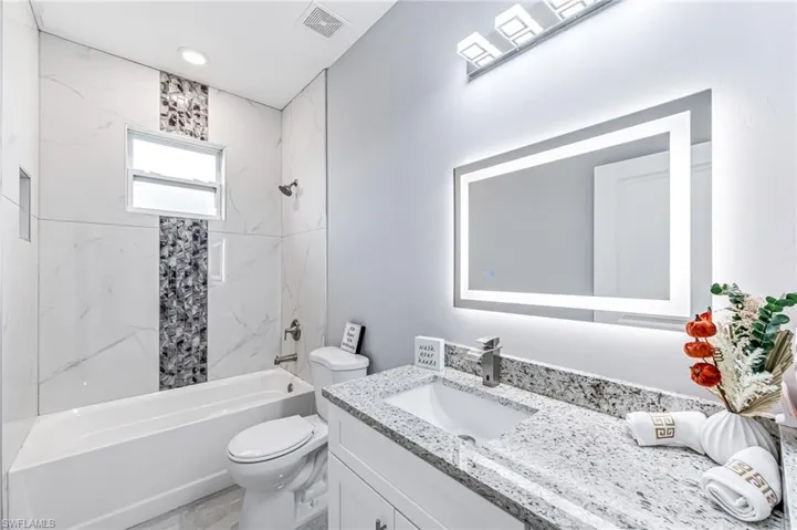 Full bathroom featuring vanity, toilet, and tiled shower / bath
